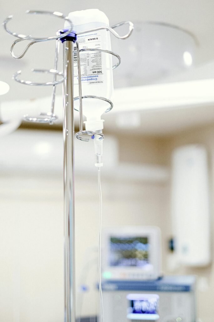 Close-up of an IV drip in a sterile hospital setting with background medical equipment.