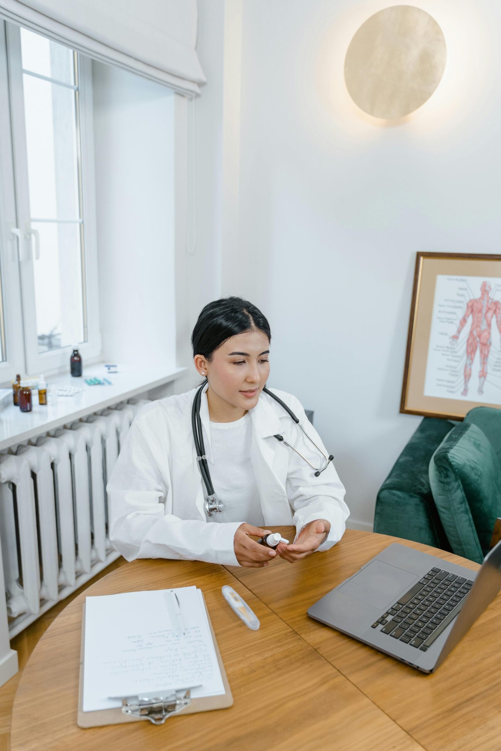 Doctor conducting a video consultation at a desk with a laptop and medical tools.